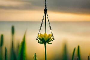 un amarillo flor colgando desde un cadena en frente de un puesta de sol. generado por ai foto
