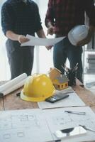 Close up of civil male engineer asian working on blueprint architectural project at construction site at desk in office. photo