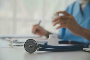 Stethoscope and background doctor using laptop at desk in clinic working on computer at room office. photo