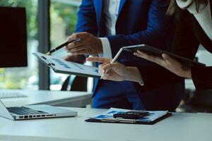 empresario empresario asiático y mujer de negocios discutiendo un nuevo proyecto de negocios en tableta en una reunión moderna en una oficina moderna, concepto casual de negocios asiáticos. foto