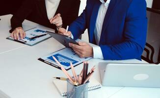 empresario empresario asiático y mujer de negocios discutiendo un nuevo proyecto de negocios en tableta en una reunión moderna en una oficina moderna, concepto casual de negocios asiáticos. foto