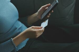 A credit card in the hands of a young businesswoman pays for a business on a mobile phone and on a desk with a laptop. photo