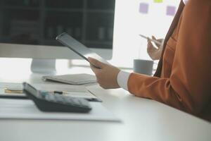 Close up Business woman using calculator and laptop for do math finance on wooden desk, tax, accounting, statistics and analytical research concept photo