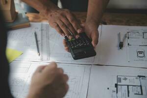 Close up of civil male engineer asian working on blueprint architectural project at construction site at desk in office. photo