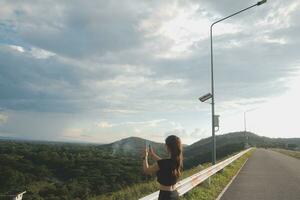 Young woman traveler in casual clothes with backpack from back on background of beautiful view on mountains photo