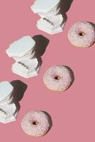 Plastic jaws with white teeth catching sweet pink donuts. Dental health, dentistry and caries concept. Colored creative art. photo