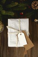 Navidad regalo etiqueta Bosquejo. blanco mínimo regalo caja en de madera mesa con festivo decoraciones foto