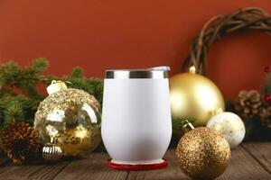 Christmas mock up of white thermo cup on wooden table with festive decorations. Golden and red Christmas colors. photo