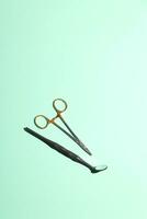 Dentist metal tools with mirror on green mint background. Minimalism. Dental care concept. photo