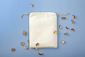Reusable Eco bag mock up for zero waste shopping on blue background with eco decorations. Minimal flat lay. photo