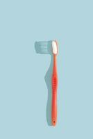 Pink toothbrush on blue background with hard shadow. Dental care concept. photo