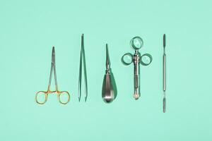 Dentist metal tools on green mint background. Minimalism. Dental care concept. Top view. photo