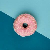 Pink donut on color block blue background. Top view layout. photo