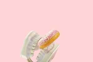 Plastic jaws hold sweet pink donut in teeth. Dental health, dentistry and caries concept. photo