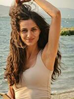 Photo of a woman with flowing hair standing by the water