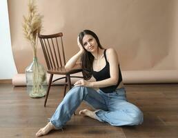 Photo of a woman sitting on the floor next to a chair