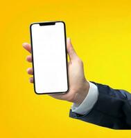 Businessman hand holding smartphone with isolated screen over yellow background. Mock up photo