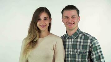 Happy young loving couple smiling to the camera, showing thumbs up video