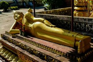 un dorado estatua de un dormido Buda tendido en el suelo foto