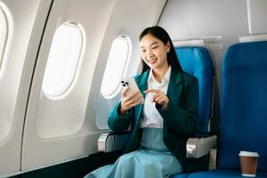 Young Asian executive excels in first class, multitasking with digital tablet, laptop and smartphone. Travel in style, work with grace. photo