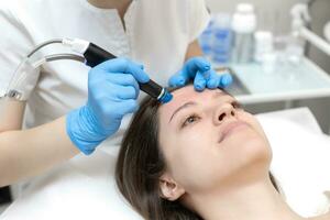Woman receiving hydrafacial treatment in beauty salon photo