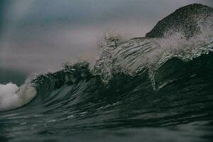 un ola rotura en el Oceano con oscuro borroso cielo en antecedentes foto