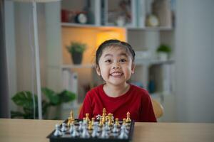 Education studying concept. Little cute asian baby girl children playing chess in the living room at home.Smart kid.fashion children. Little genius Child. Intelligent game.Chessboard. photo