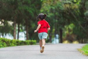 contento bebé asiático niña sonriente. pequeño niña corriendo y sonriente a puesta de sol contento bebé niña sonriente. pequeño bebé corriendo a puesta de sol. linda bebé corriendo a patio de recreo jardín. foto