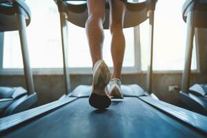 Close up of feet, sportman runner running on treadmill in fitness club. Cardio workout. Healthy lifestyle, guy training in gym. Sport running concept. photo