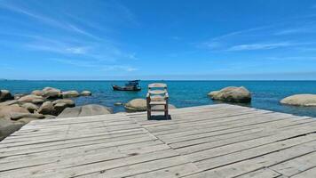 un de madera silla en un de madera muelle azul mar grande piedras pequeño tropical isla video