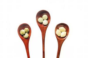 Multivitamins, multimineral, and phytonutrients are pressed tablets as nutritional supplements placed on a wooden spoon with isolated on white background. photo