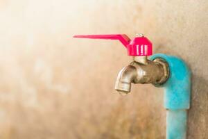 Shot of selective focus old faucet doesn't close properly and dripping water leaks out photo