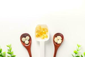 Top view variety of vitamins, minerals, and fish oil in pill form on a wooden spoon isolated on a white or transparent background. Dietary food supplements are a new alternative to health care. photo