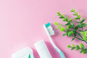 Pastel pink background with cleaning tools for oral and dental health care such as toothbrush, toothpaste, and floss. Lifestyle and daily routine for a healthy mouth and teeth. photo