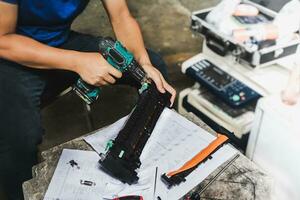 A technician is using an electric drill to tighten the drum's nuts to disassemble it, repair it and clean it. photo