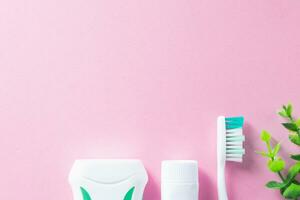 Pastel pink background with cleaning tools for oral and dental health care such as toothbrush, toothpaste, and floss. Lifestyle and daily routine for a healthy mouth and teeth. photo