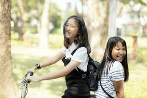 alegre asiático adolescente felicidad emoción montando bicicleta en público parque foto