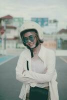 asiático mujer vistiendo blanco la seguridad casco en pie en ciudad la carretera con dientes sonriente con felicidad foto