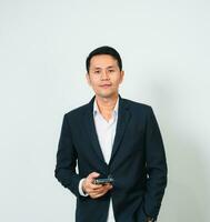 Asian businessman in suit with using mobile standing studio isolated on gray background, young business man is manager or executive smiling and confident is positive success. photo