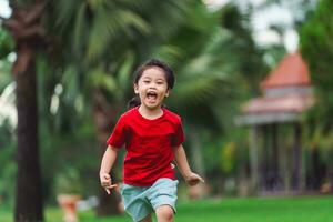 contento bebé asiático niña sonriente. pequeño niña corriendo y sonriente a puesta de sol contento bebé niña sonriente. pequeño bebé corriendo a puesta de sol. linda bebé corriendo a patio de recreo jardín. foto