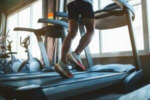 Close up of feet, sportman runner running on treadmill in fitness club. Cardio workout. Healthy lifestyle, guy training in gym. Sport running concept. photo