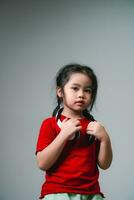 Cheerful happy asian children girl with black hair listening to music songs in headphones on a gray background. Portrait cute girl waring red shirt and looking at camera studio lighting. photo