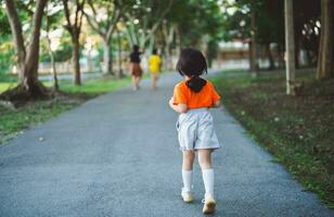 contento bebé asiático niña sonriente. pequeño niña corriendo y sonriente a puesta de sol contento bebé niña sonriente. pequeño bebé corriendo a puesta de sol. linda bebé corriendo a patio de recreo jardín. foto