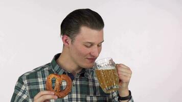 Young attractive man laughing joyfully, sipping delicious beer, holding a pretzel video