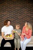 Family with a mother, father and daughter sitting outside on the steps of a front porch of a brick house photo