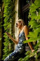 Pretty young woman using mobile phone by the old house with ivy photo