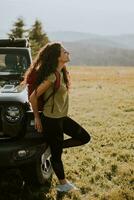 joven mujer relajante por terreno vehículo capucha a campo foto