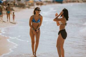 Two pretty young woman having fun on the seaside photo