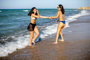 Two pretty young woman having fun on the seaside photo