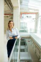 Young woman with notebook standing in the modern office hallway photo
